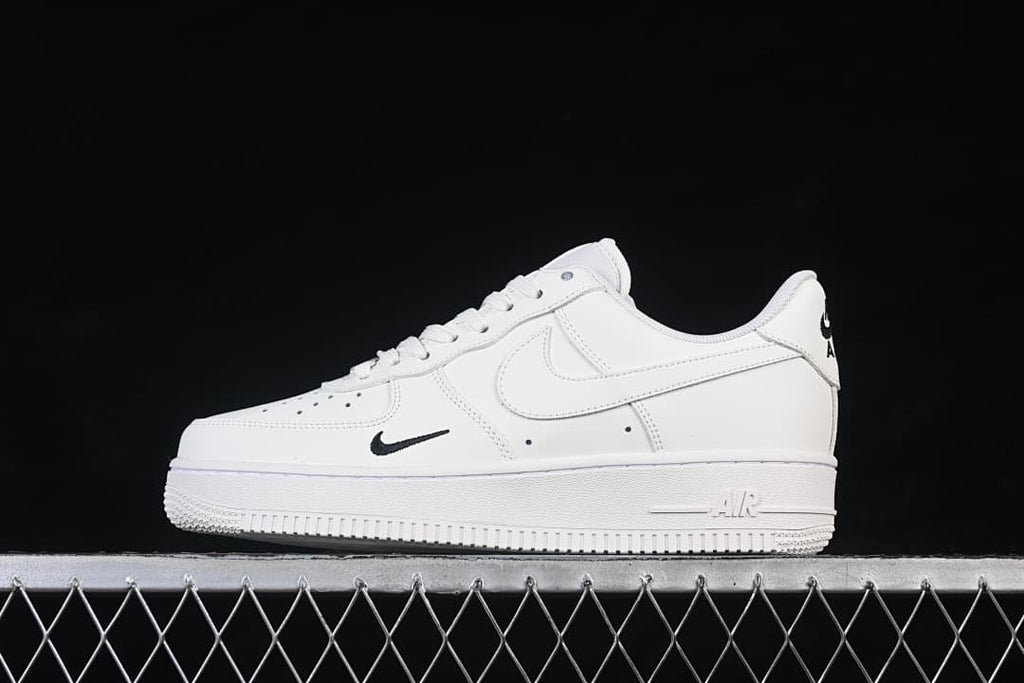 Side view of a white low-top Air Force 1 ’07 sneaker with small black Swoosh accents