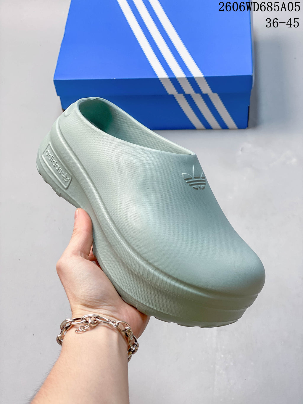 Angled side view of a light blue Adidas mule shoe
