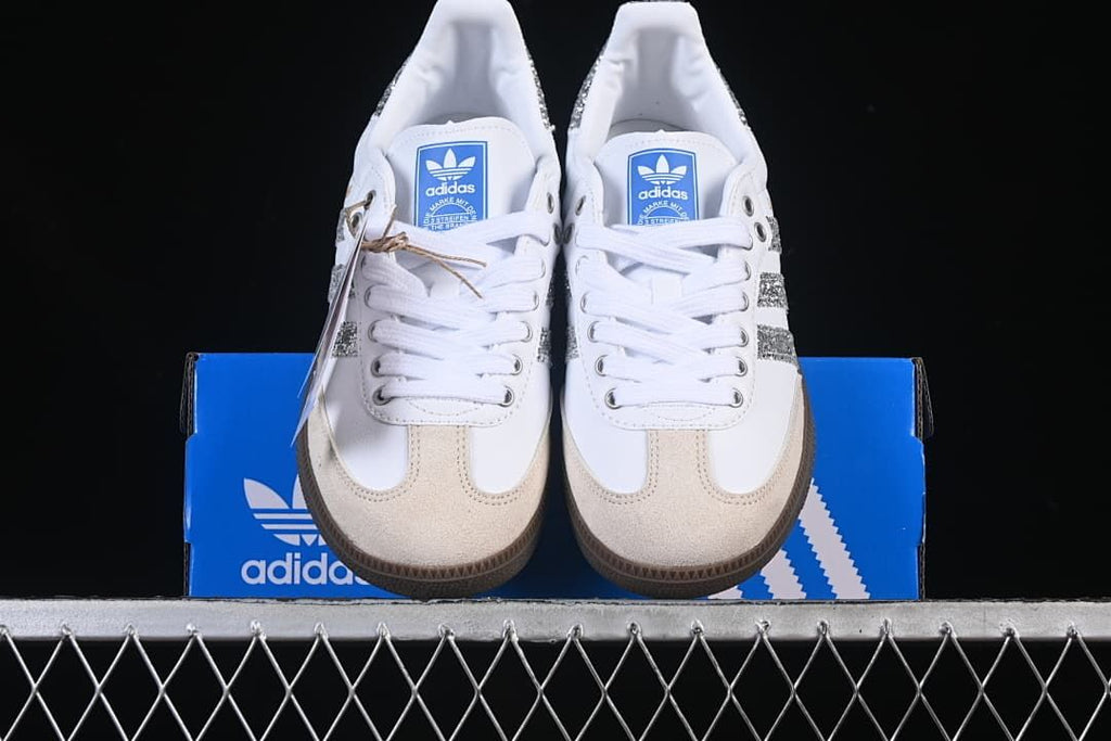 Front view of the pair of white sneakers with beige toe overlays and silver accents.