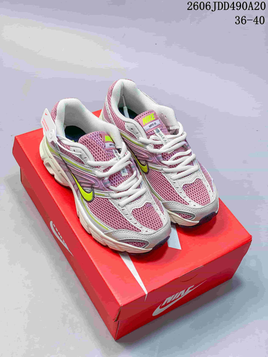 Pair of pink, white, and lime Nike Air Max Moto 2K sneakers displayed on a red shoe box