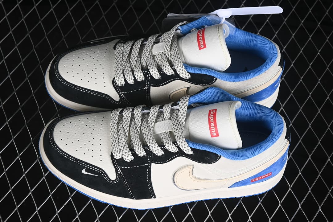 Pair of white, black, and blue Air Jordan 1 Low sneakers with patterned laces and visible Supreme tongue branding.