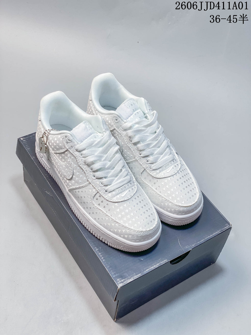 Pair of white patterned Nike Air Force 1 low-top sneakers with white laces, displayed on a box.