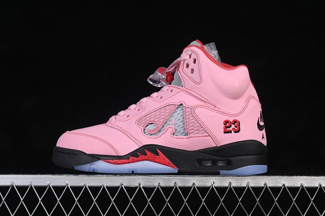 Side view of a pink Awake NY x Air Jordan 5 sneaker with red details, a black midsole, and translucent outsole.