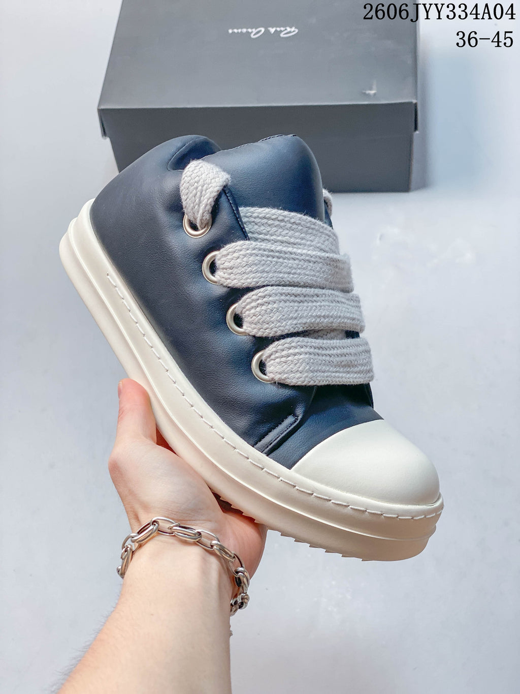 Angled close-up of the navy sneaker upper, metal eyelets, wide laces, and ivory sole