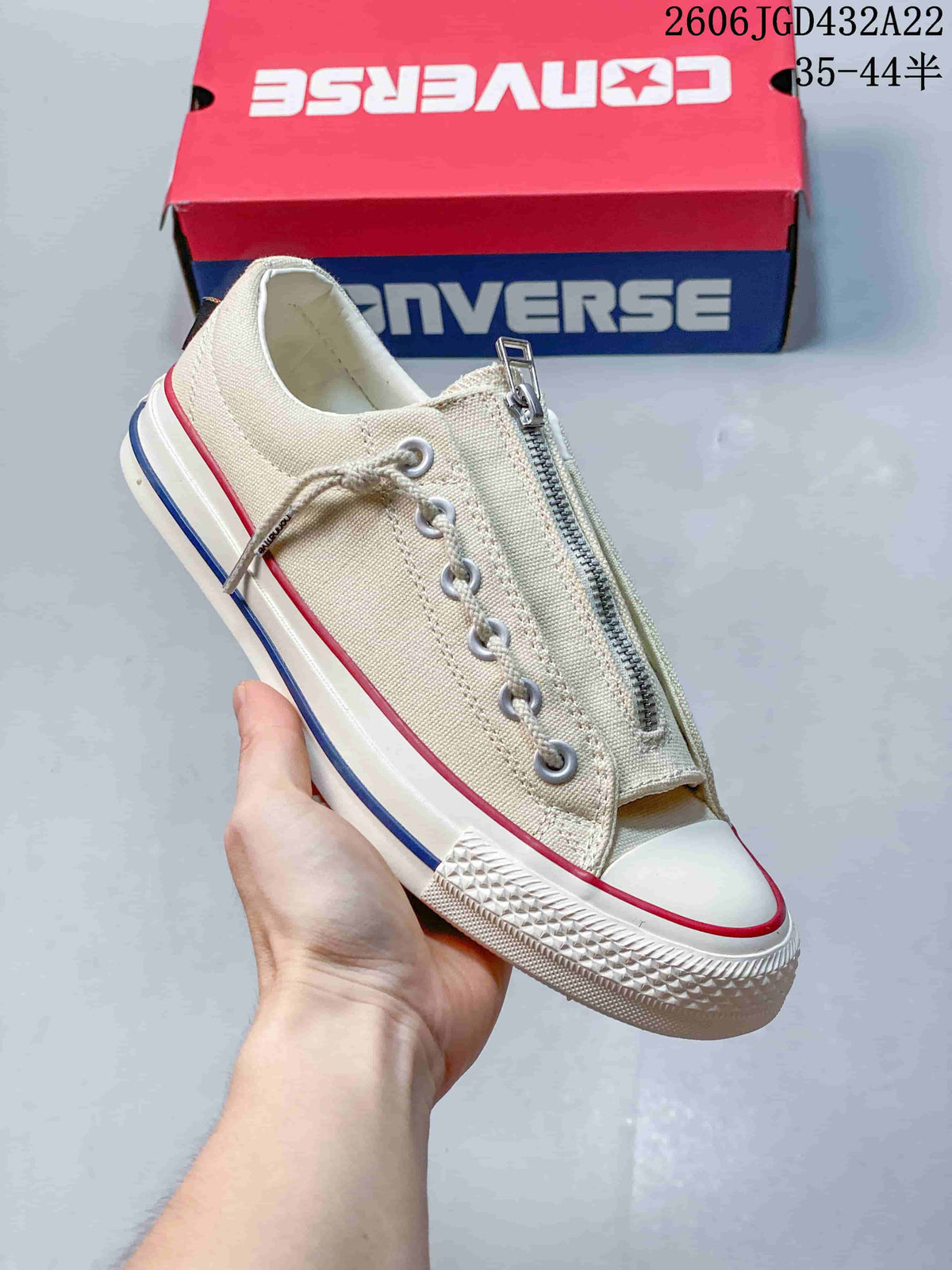 Angled view of the cream sneaker with zipper closure and raised rubber sole