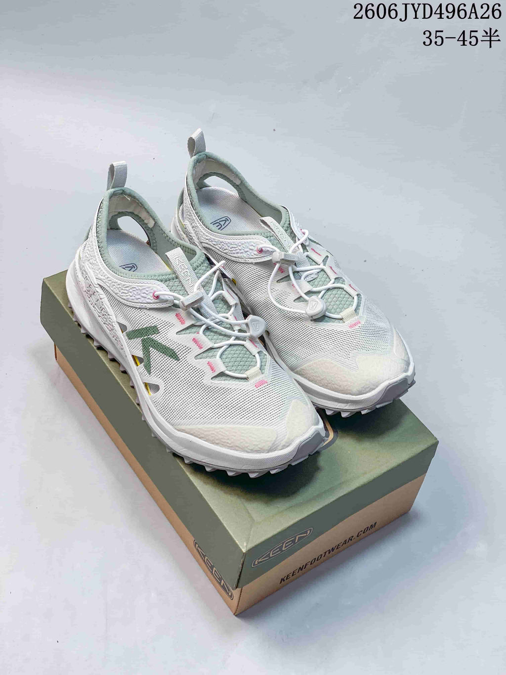 White low-top hiking shoes with green and pink accents on a box