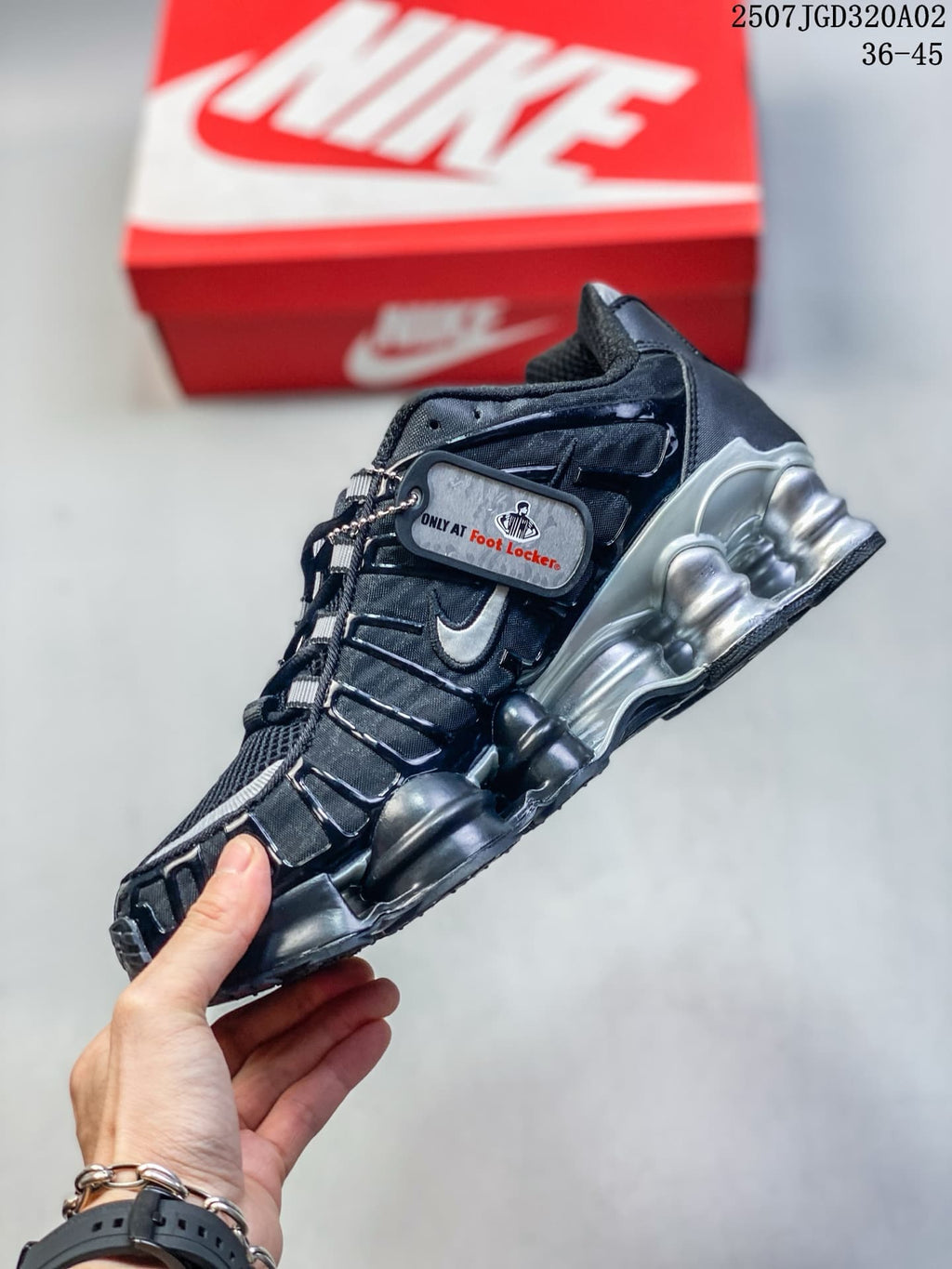 Side view of a black and silver Nike Shox TL sneaker with a hanging tag