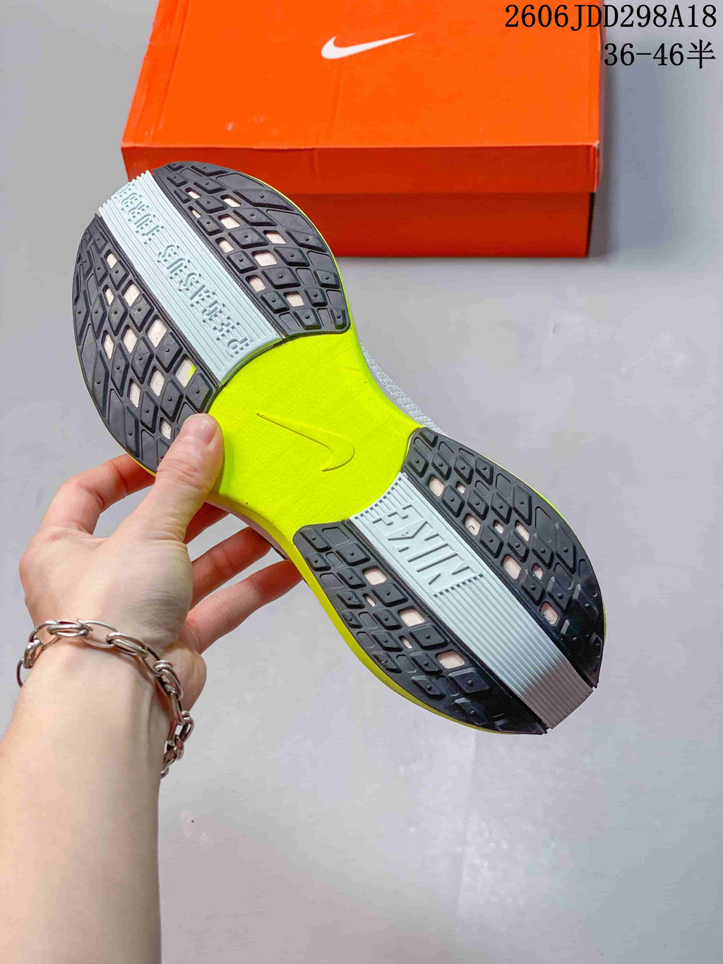 Underside of the running shoe showing a patterned black outsole and bright volt center section