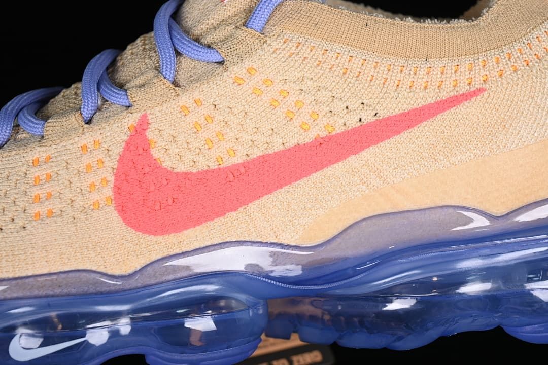 Close-up of the coral-pink Swoosh, knit upper, lavender laces and blue sole.