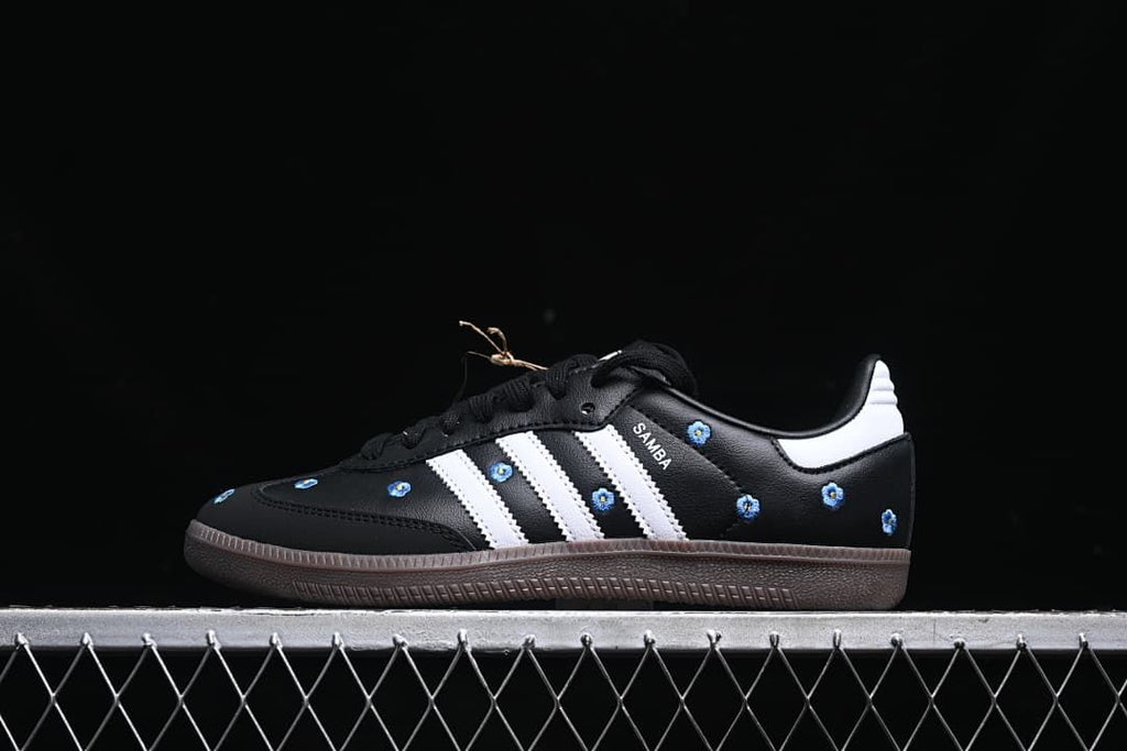 Side profile of a black Samba OG shoe with white stripes and blue floral embroidery