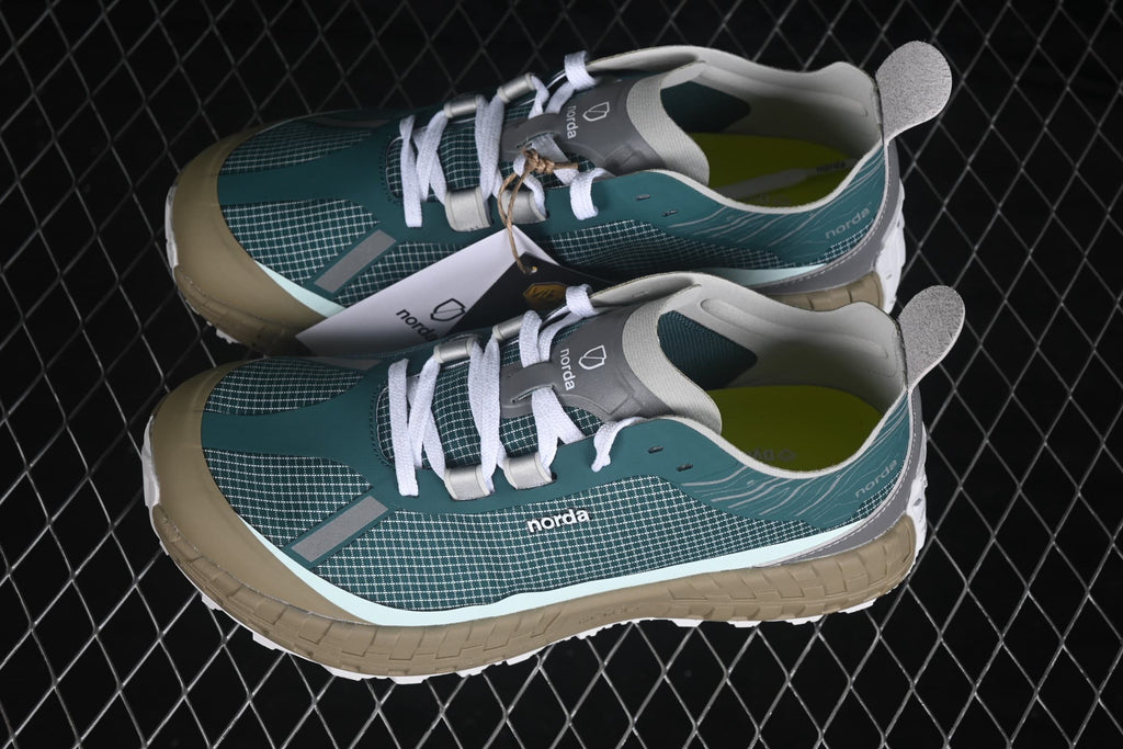 Overhead angled view of the pair displaying the green patterned uppers, white laces, and tan midsoles.