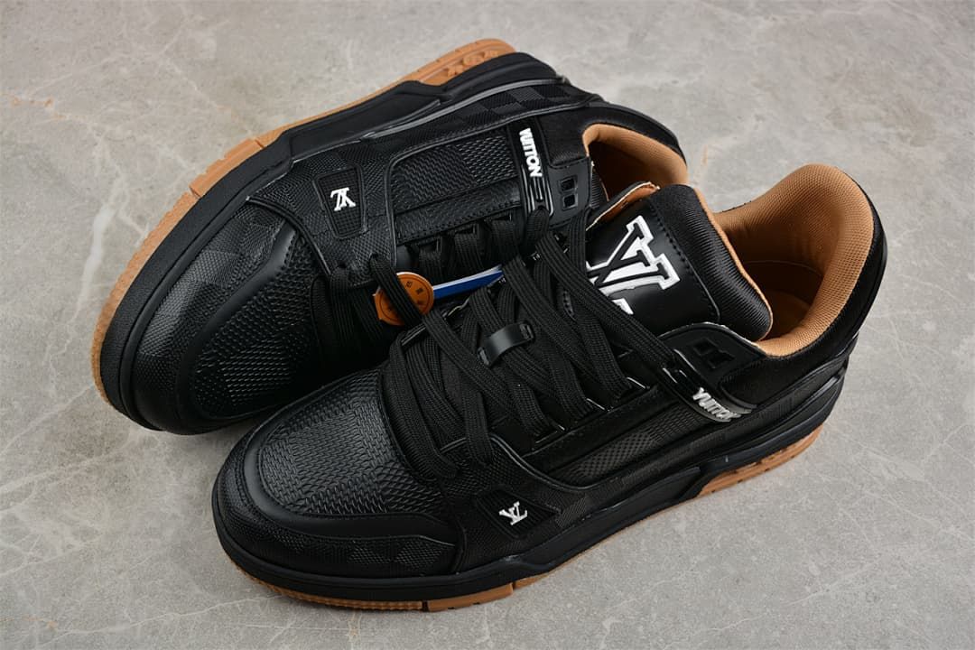 Pair of black low-top sneakers with tan-colored outsoles, photographed from above