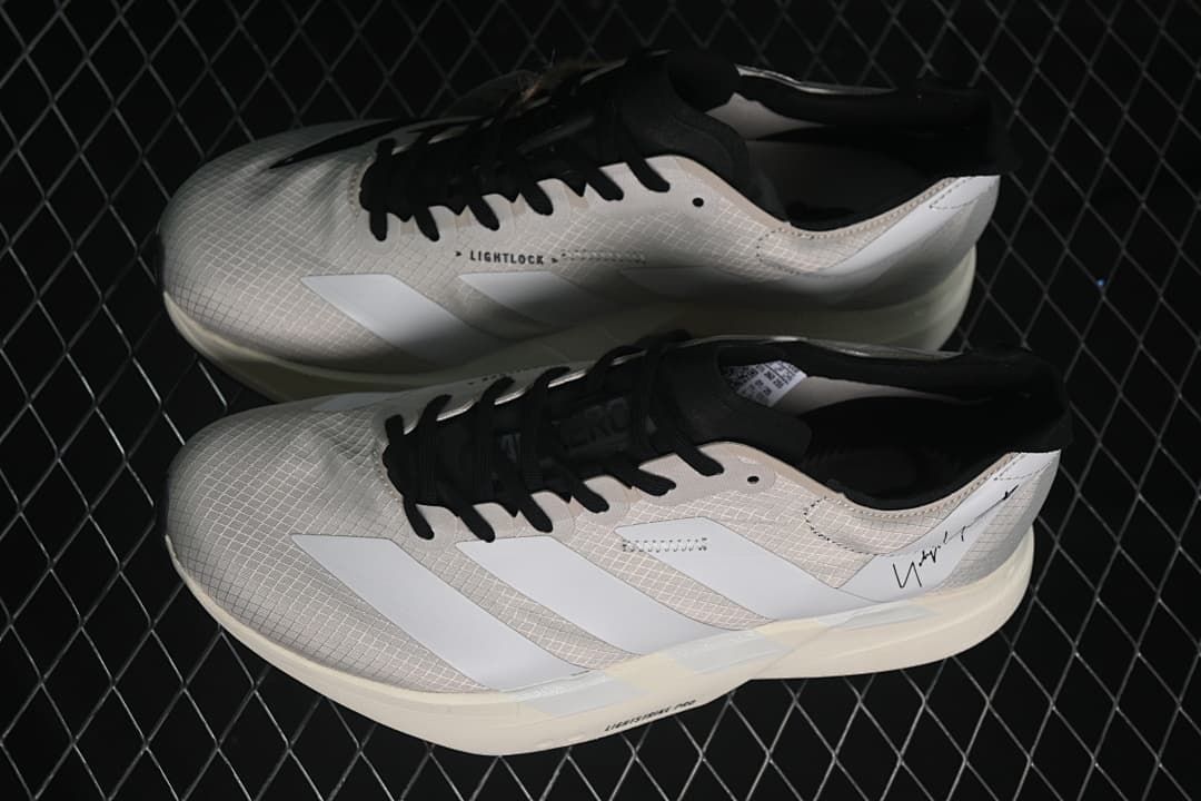 Pair of beige and white running shoes with black laces, shown from the side