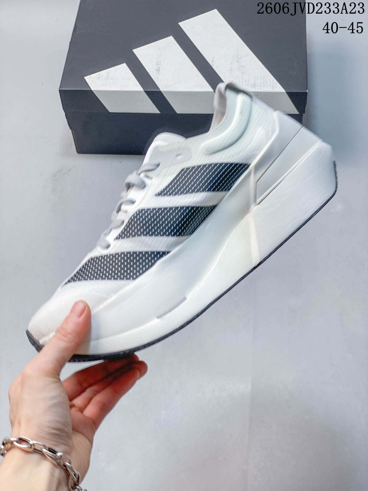 Side view of a white adidas running shoe with dark patterned stripes and a sculpted midsole