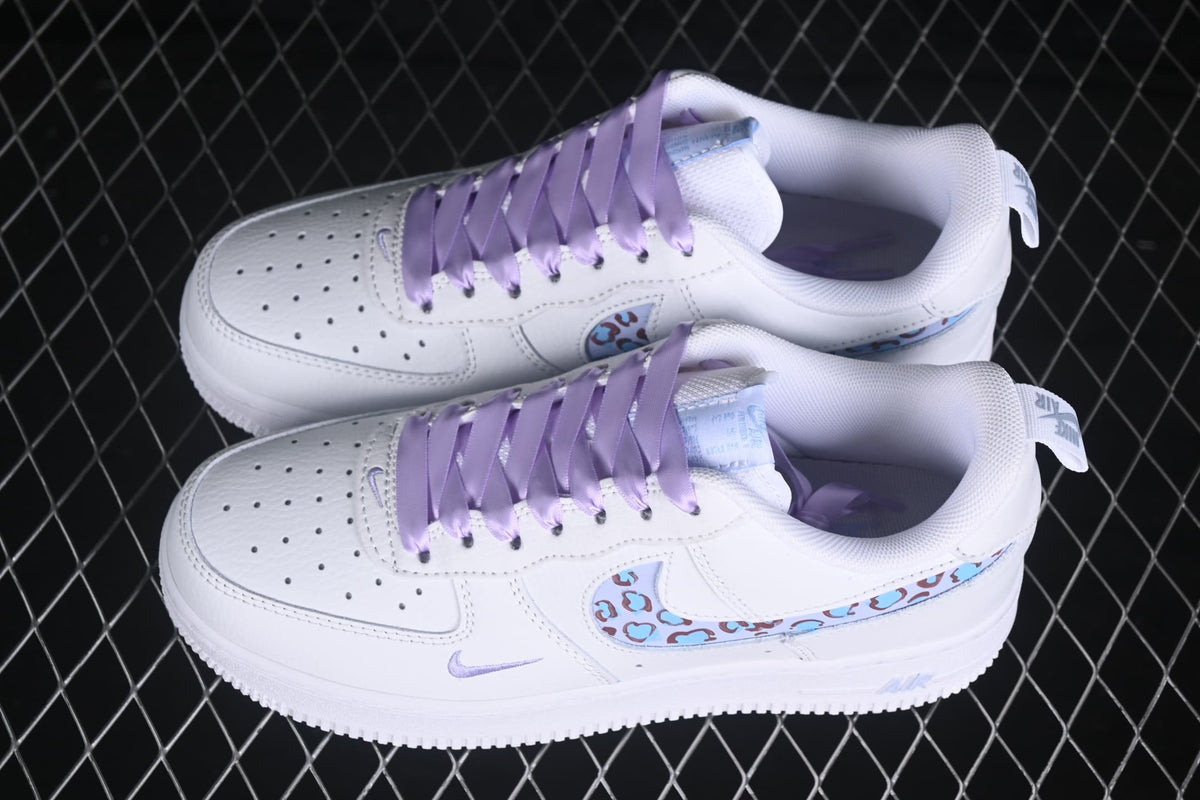 Pair of white Nike low-top sneakers with lavender laces and pale blue leopard-pattern Swooshes.