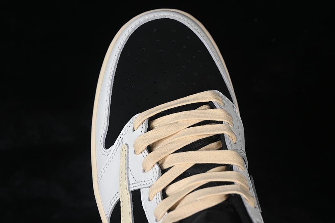Close-up of the black perforated toe, white overlays, and cream laces.