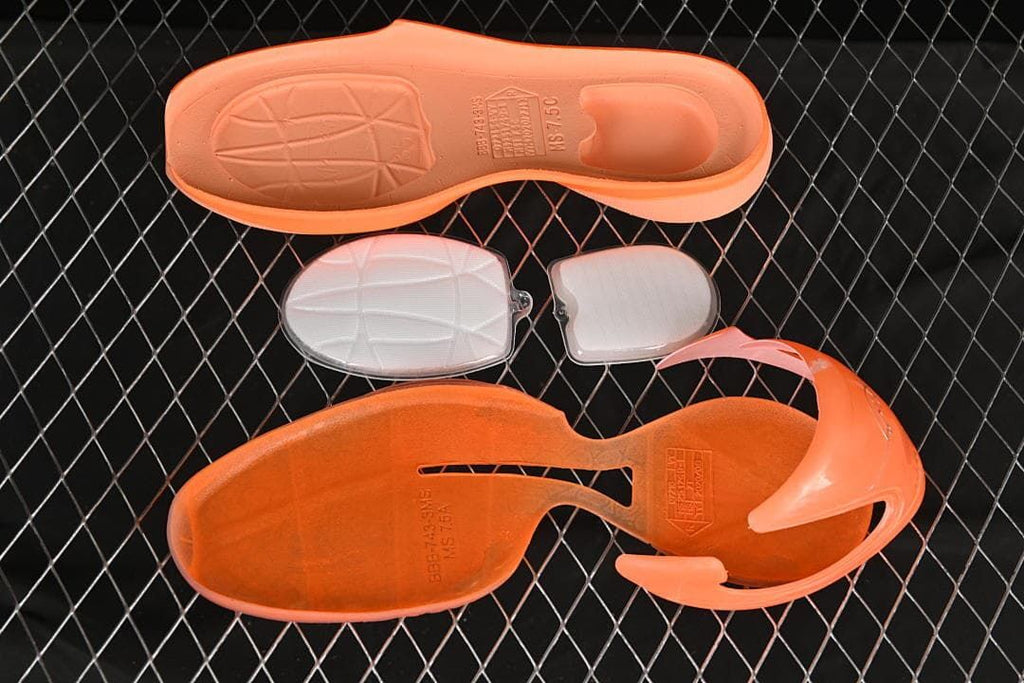 Disassembled orange shoe components shown from above