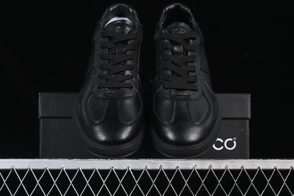Front view of the pair of black sneakers on a shoe box