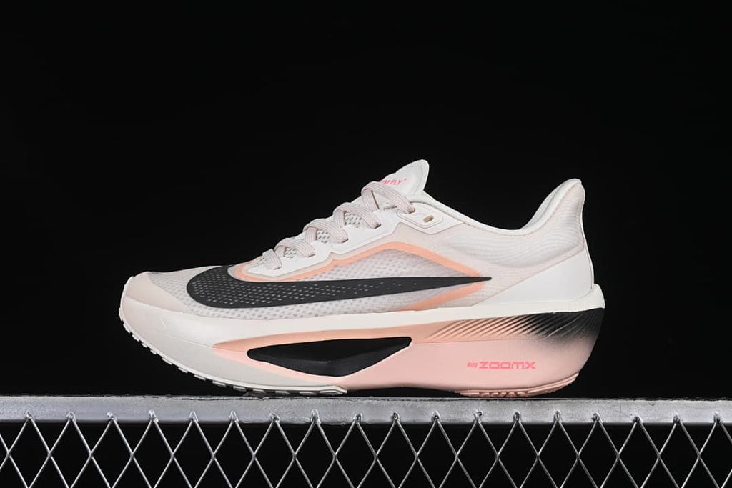 Side view of a white Nike Zoom Fly 6 shoe with pink accents and black Swoosh