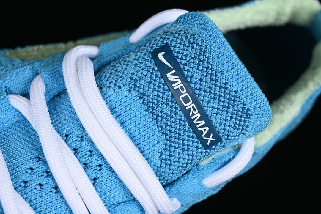 Close-up of the tongue label and white laces on the blue knit shoe.