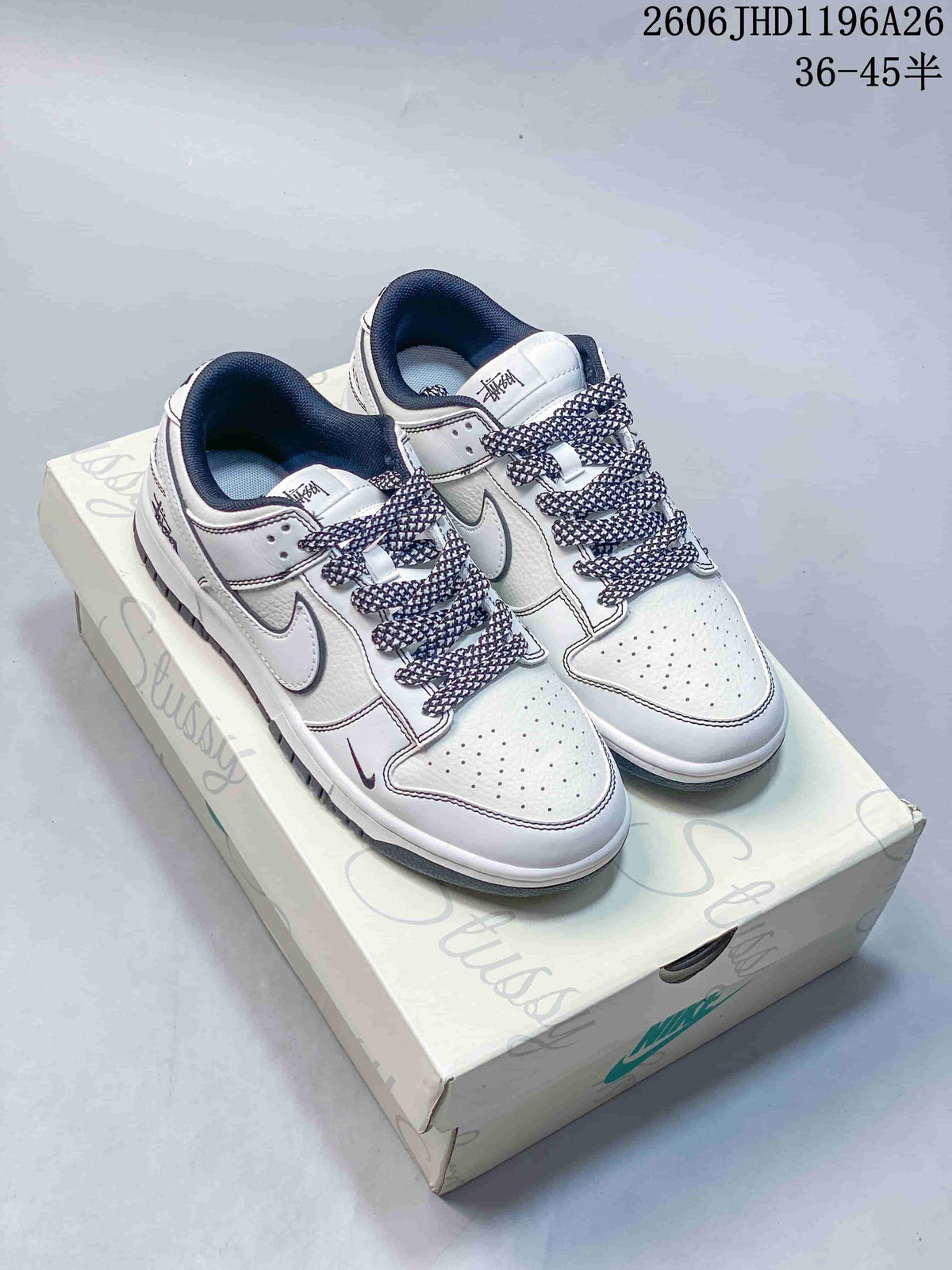 Pair of white low-top sneakers with dark patterned laces and contrasting trim.