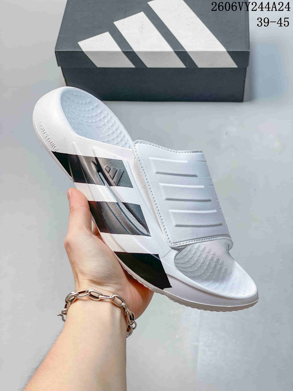 White adidas Lightblaze slide with dark stripe details and a textured footbed; image overlay lists sizes 39–45.