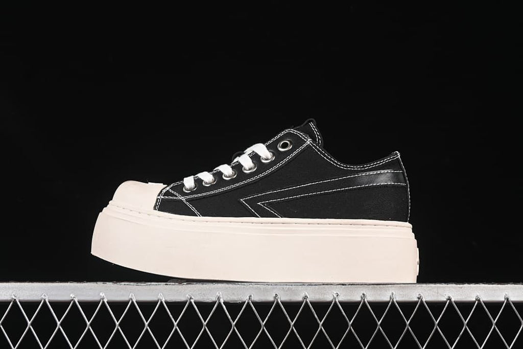 Side view of black SMFK low-top sneakers with white stitching and a thick light-colored platform sole.