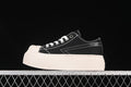 Side view of black SMFK low-top sneakers with white stitching and a thick light-colored platform sole.