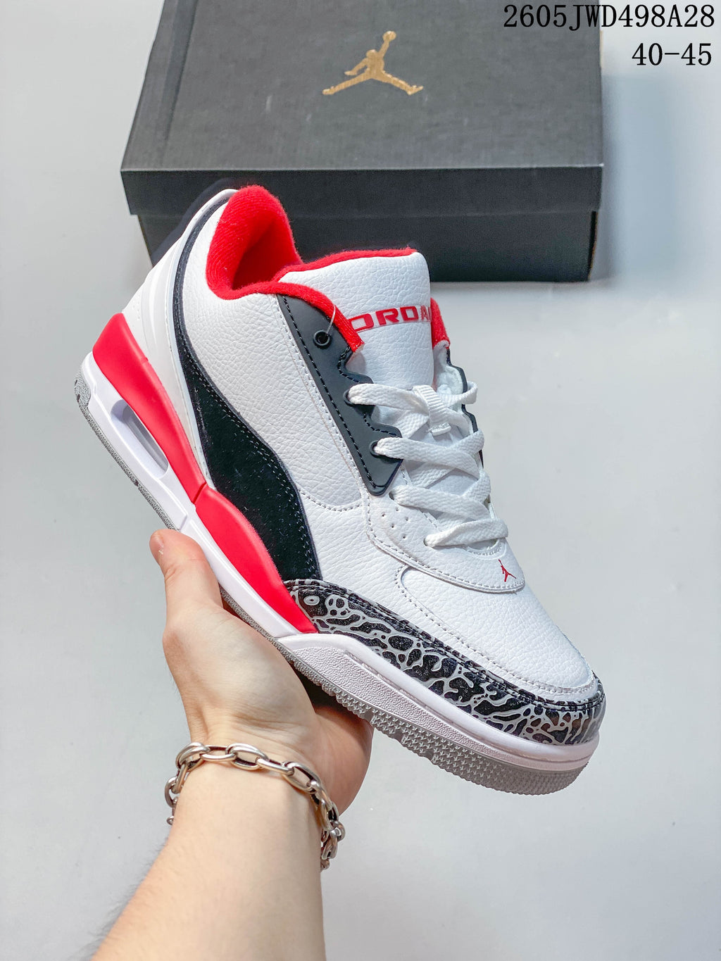 Side profile of a white low-top Jordan sneaker with red and navy details and elephant-print toe trim