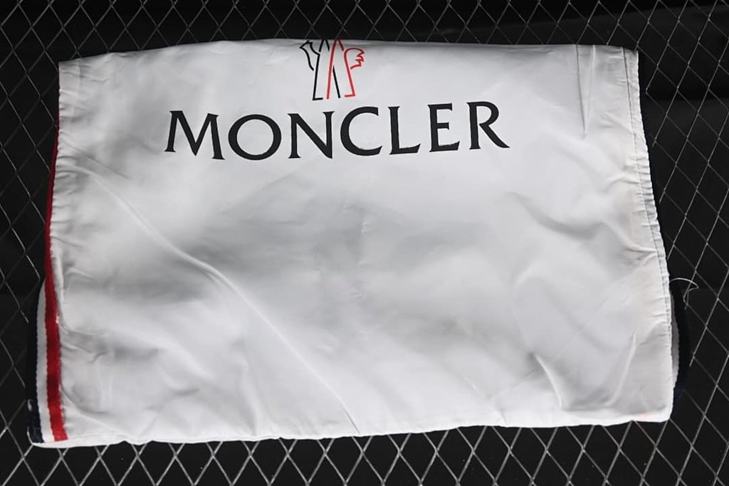 White branded shoe bag photographed against a dark fence