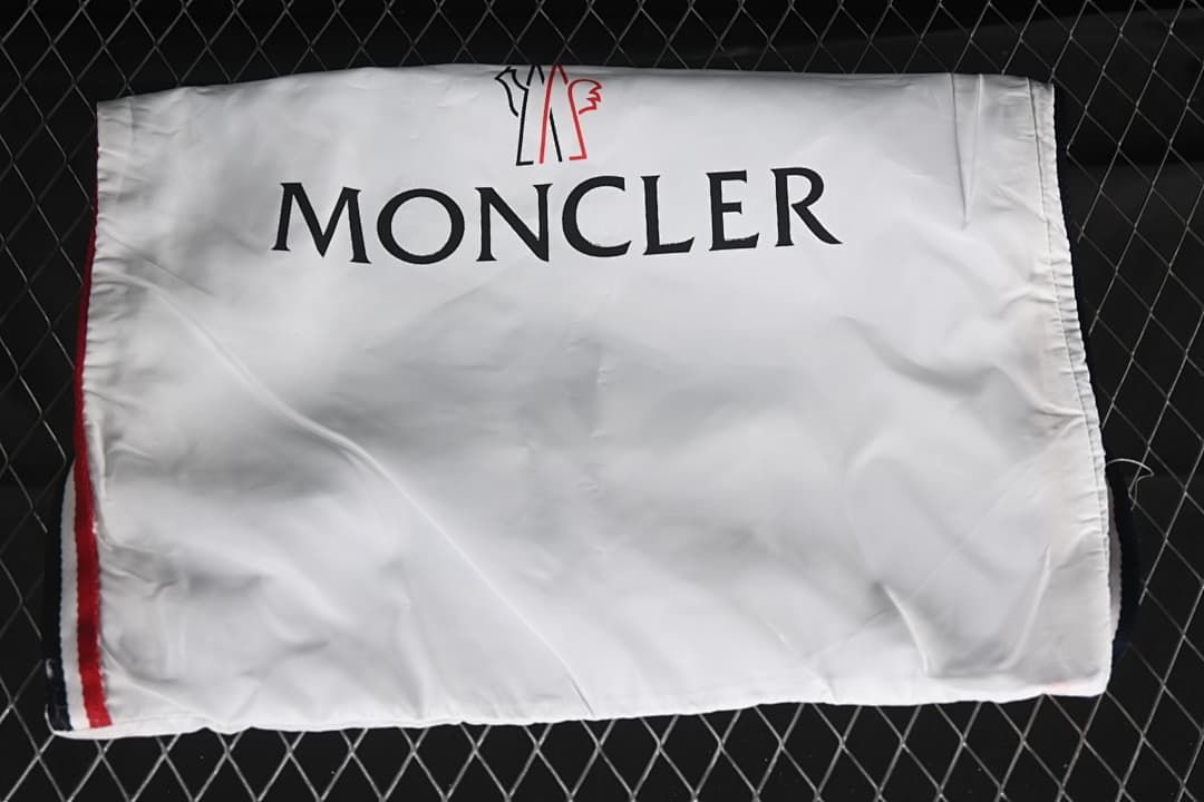 White branded shoe bag photographed against a dark fence