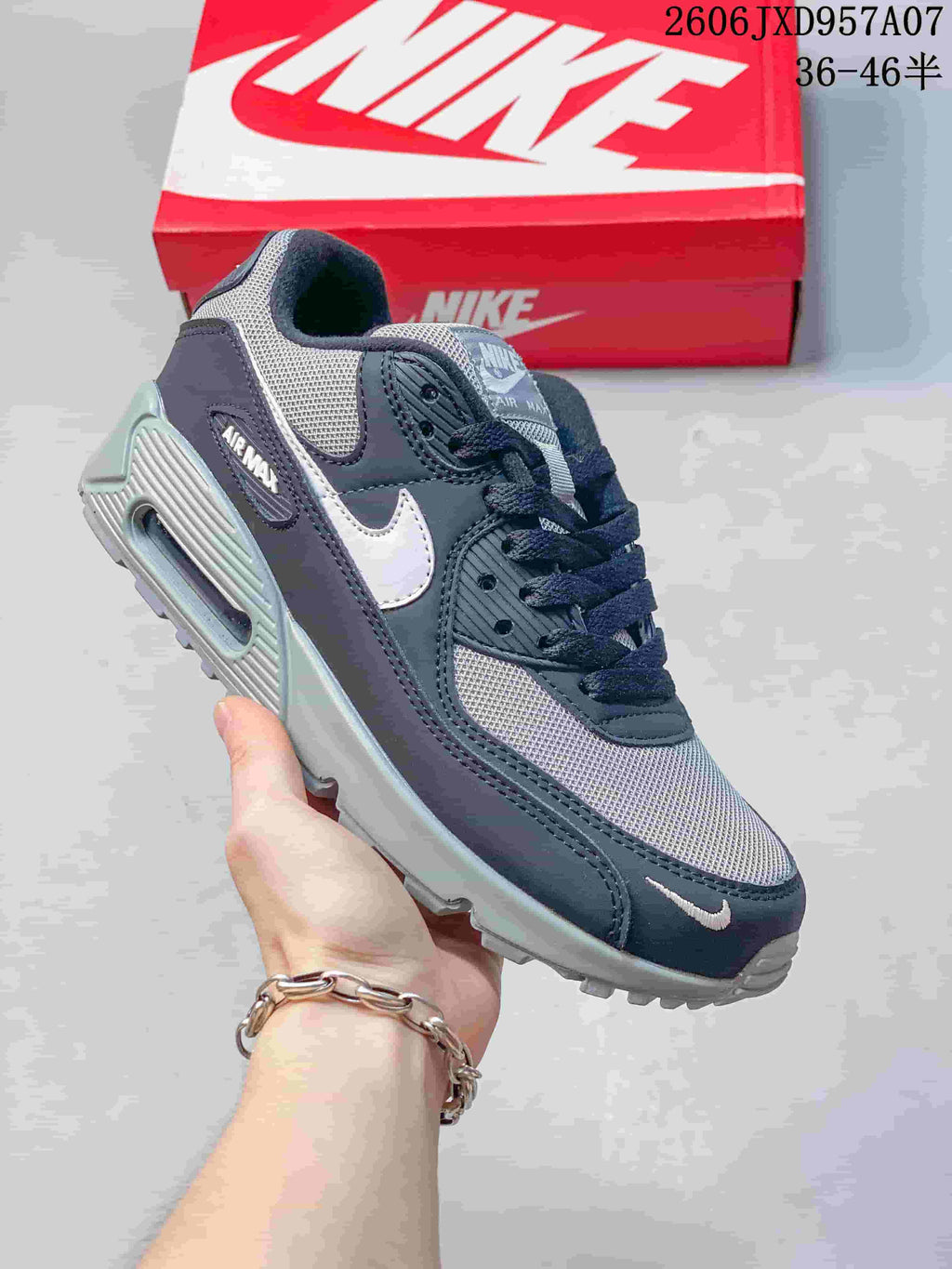 Angled side view of a navy and gray Nike Air Max 90 sneaker with a white Swoosh and visible Air unit.