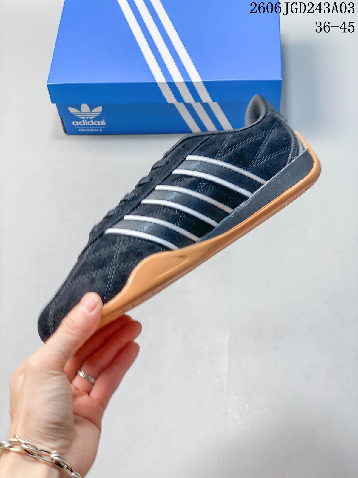 Side profile of the black sneaker with light-colored stripes and a gum-colored sole