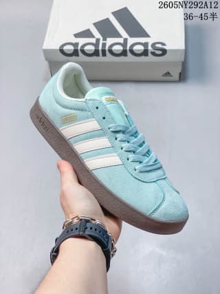 Angled side view showing the pale sea blue upper, three off-white stripes, and gum-colored sole.