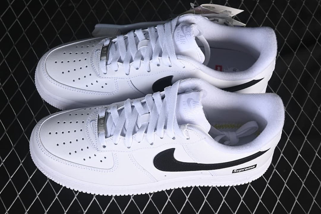 Pair of white low-top sneakers with black Swooshes