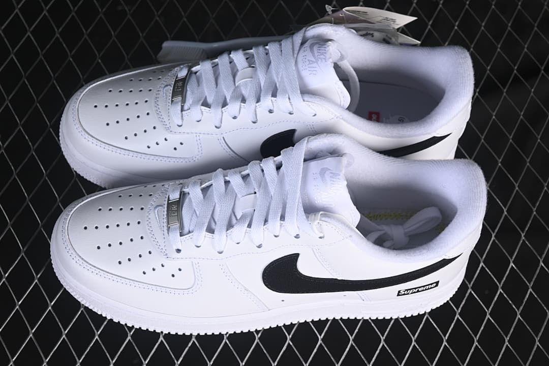 Pair of white low-top sneakers with black Swooshes