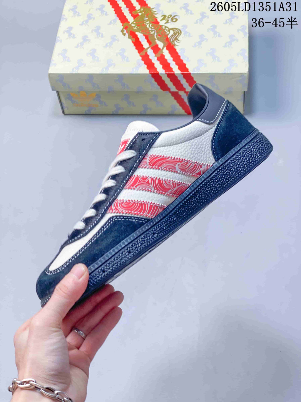 Side view of the sneaker with red patterned stripes, navy overlays, and white panels