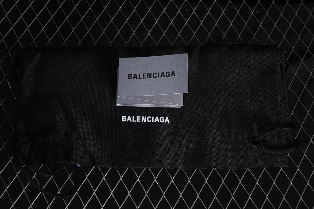 Black branded dust bag and booklet photographed with the sneakers.