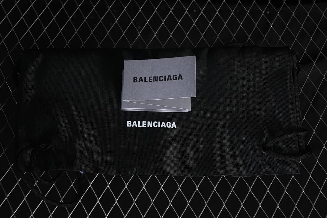 Black branded dust bag and booklet photographed with the sneakers.