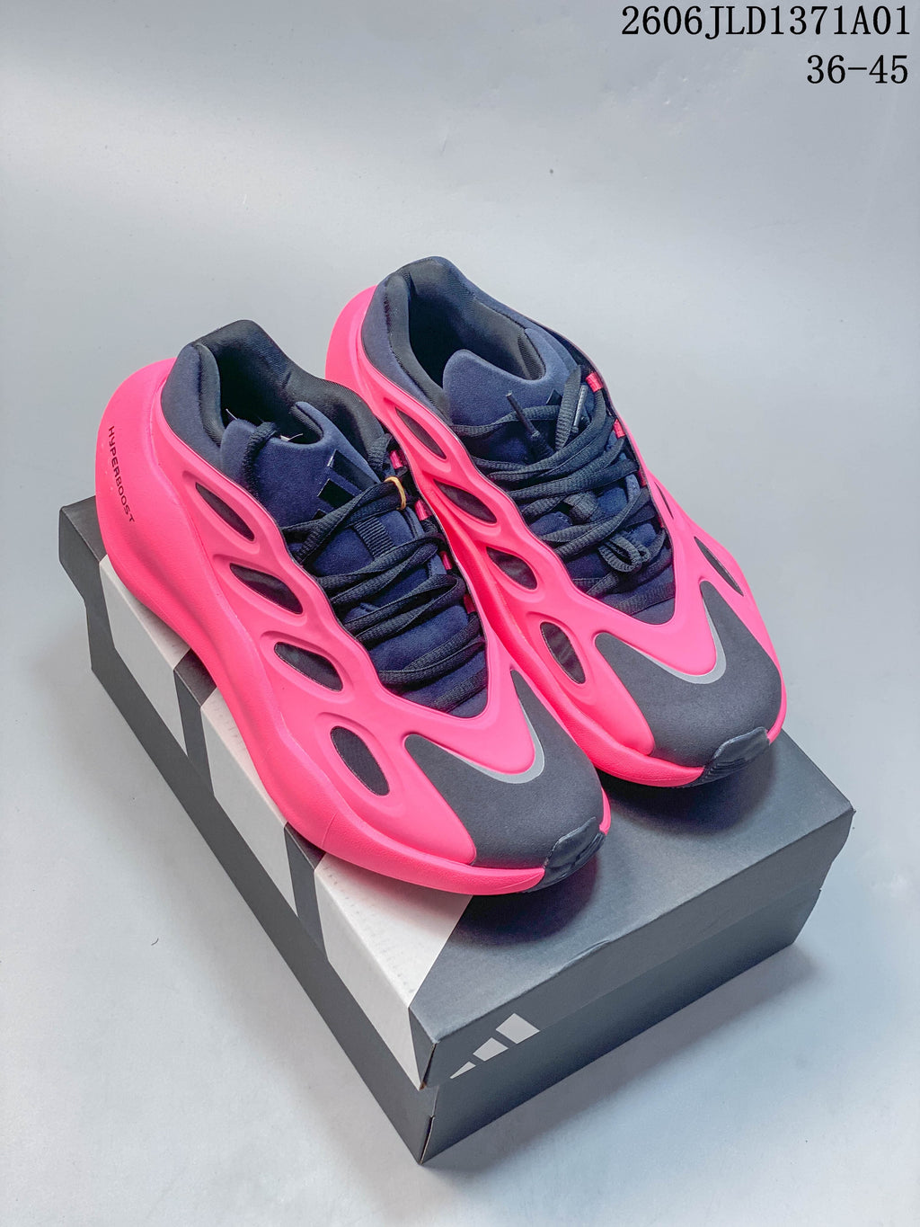 Pair of Adidas Hyperboost sneakers in pink, navy, and charcoal, shown from above on a shoe box.