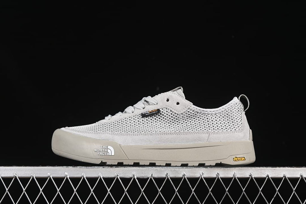 Side view of a grey The North Face low-top sneaker against a dark background.