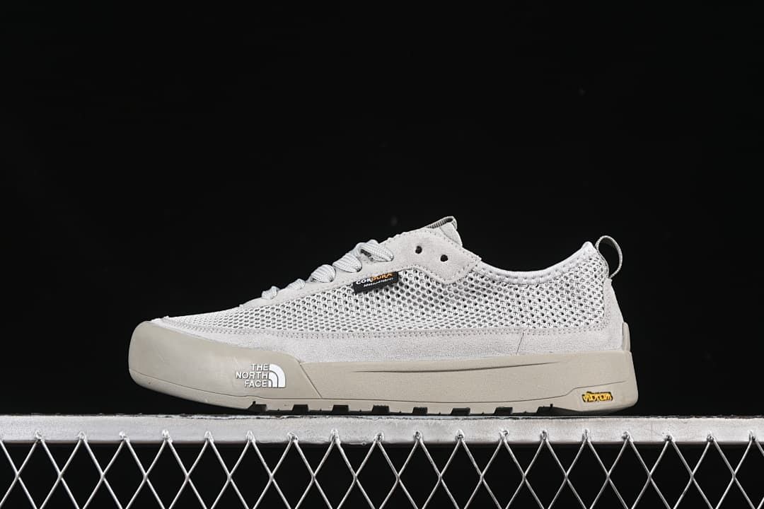 Side view of a grey The North Face low-top sneaker against a dark background.
