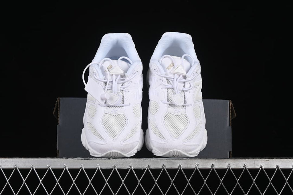 Pair of white sneakers viewed from the front on a shoe box.