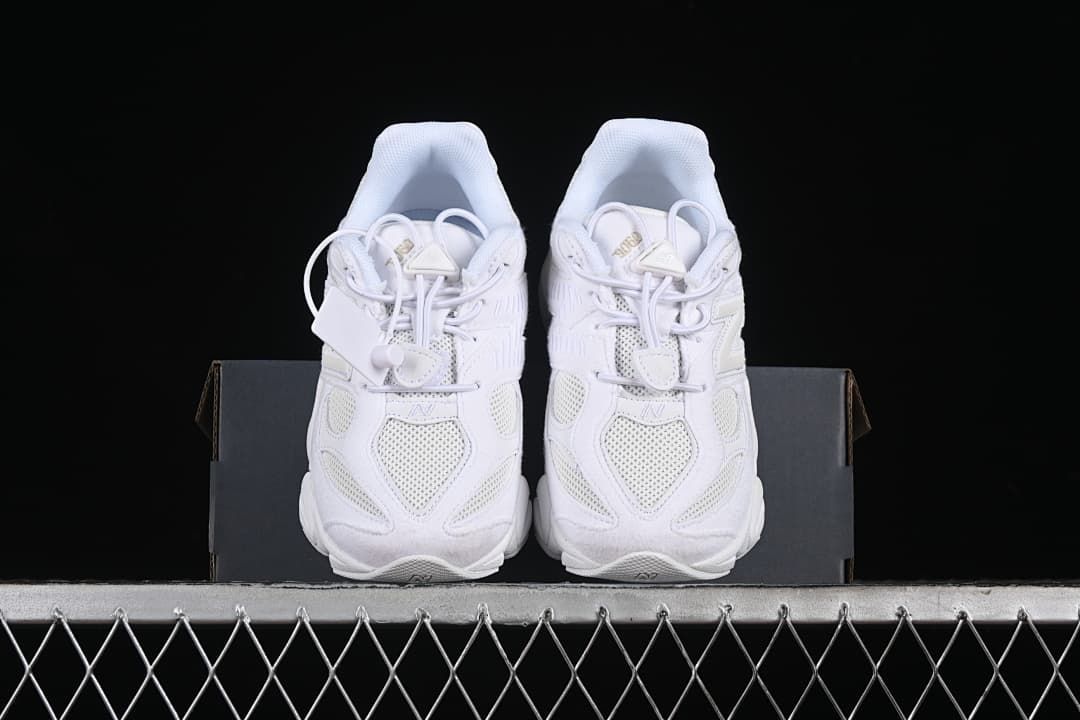Pair of white sneakers viewed from the front on a shoe box.