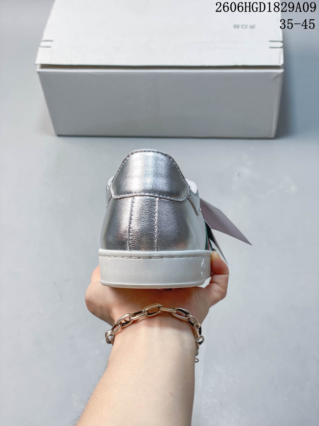 Rear view of a silver low-top sneaker with a white sole.