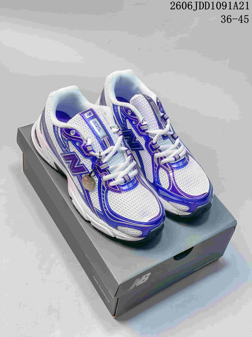 Pair of white and blue-purple New Balance 740 sneakers displayed on a shoebox