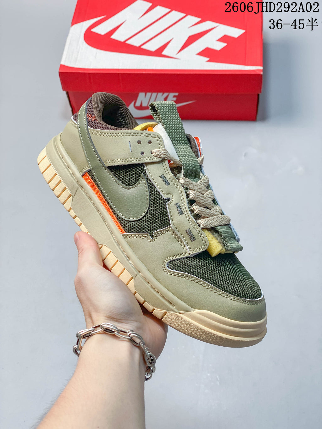 Olive and dark green Nike SB Dunk low-top sneaker with orange accents, shown beside a Nike shoe box.