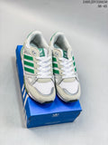 Pair of white and green Adidas ZX 750 sneakers shown from the front on a blue shoe box