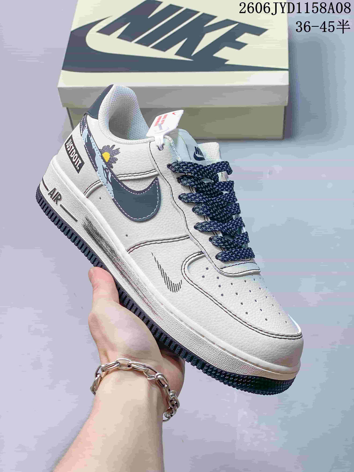 Angled side view of the white sneaker with navy accents, patterned laces, and decorative flower detail.