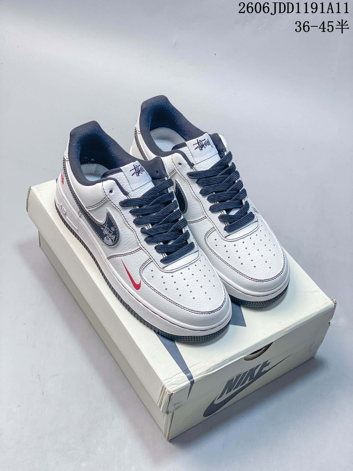 Pair of white low-top Nike Air Force 1 '07 sneakers with navy laces and red accents